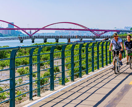 Taipei: This is a view of a riverside cycling path with people cycling and Guandu bridge in the background on a sunny day on May 29, 2017 in Taipei